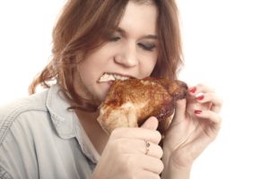 Девушка ест курицу
